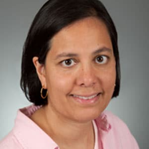 Dr. Annapruna Poduri smiling in front of a grey background.