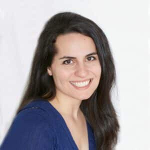 Gabriella Joseph smiles in front of a white background wearing a blue top.
