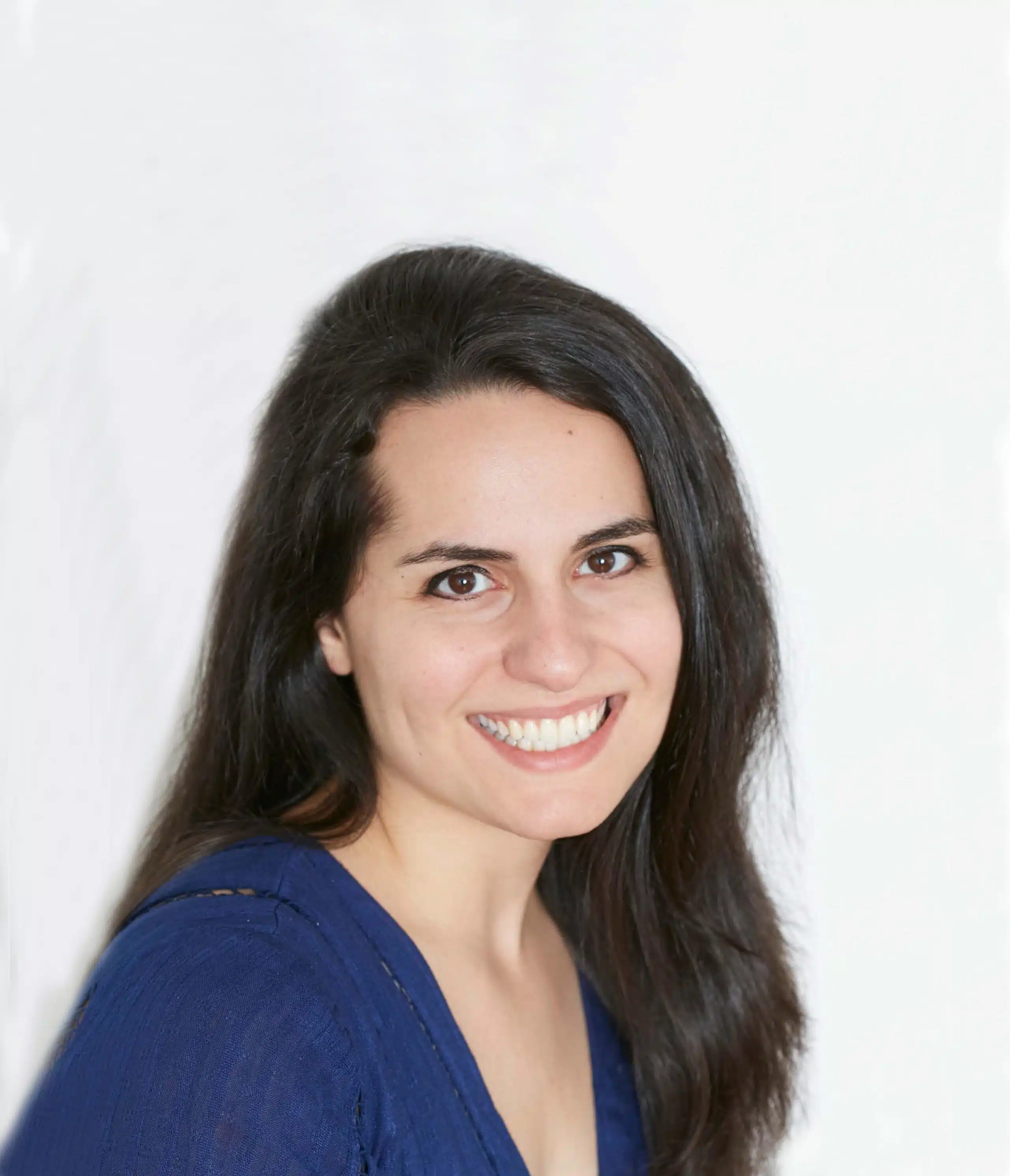 Gabriella Joseph smiles in front of a white background wearing a blue top.