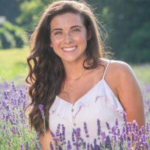 Madelyn Rose Samuel smiles while in a field of purple flowers.