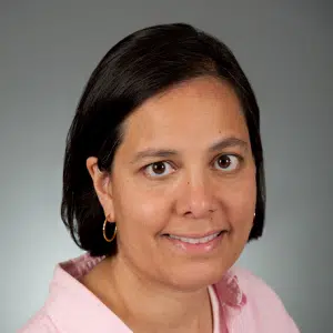 Headshot of woman wearing a pink shirt smiling at the camera.