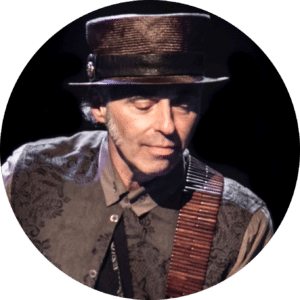 The legendary Nils Lofgren looks down toward his guitar while performing.