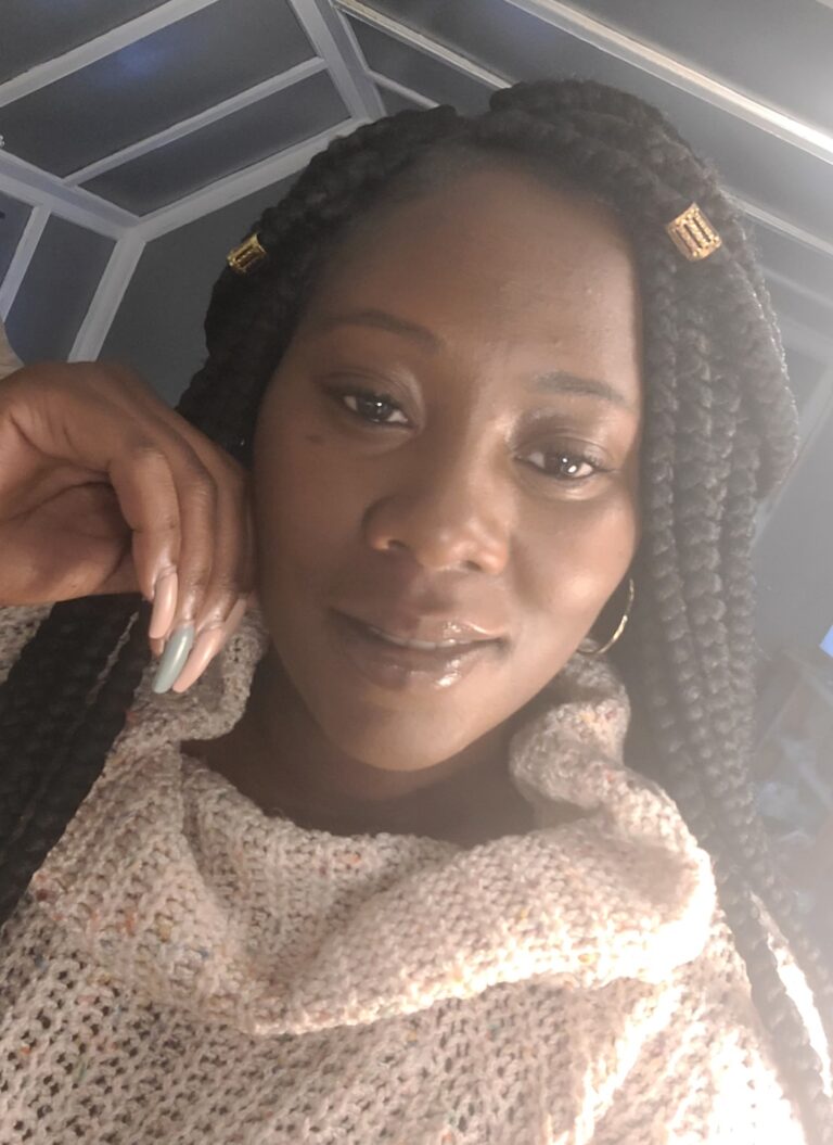 a woman with braids and a white sweater smiling