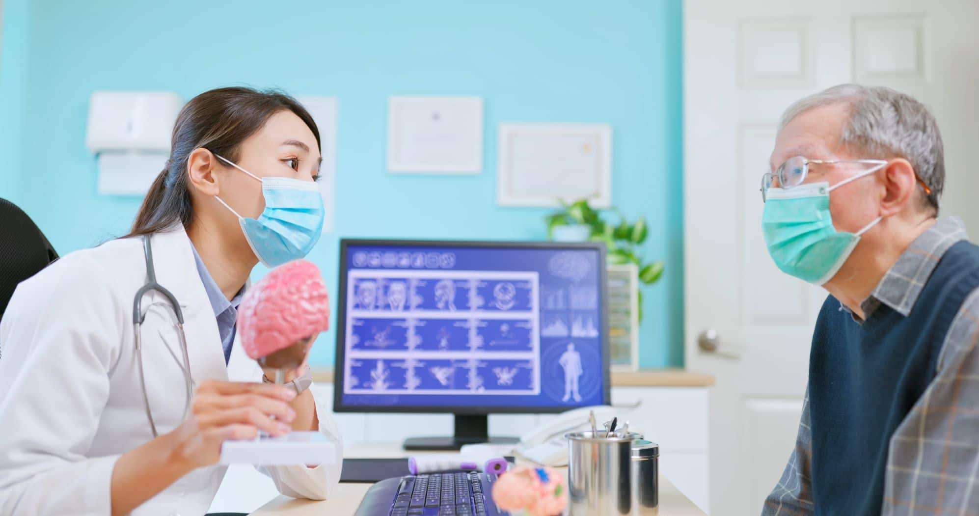 Doctor wearing a stethoscope, lab coat, and mask talks with older patient