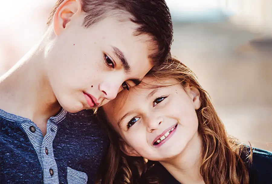 Photo of young boy resting his head on a younger girl for support