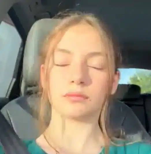Photo of young woman in the car with eyes closed in the sunlight