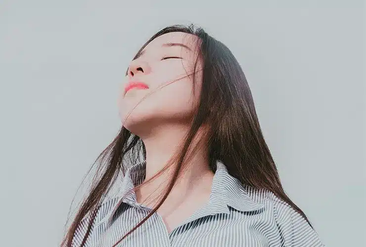 Person with Jeavons Syndrome standing with their eyes closed and head tilted upwards