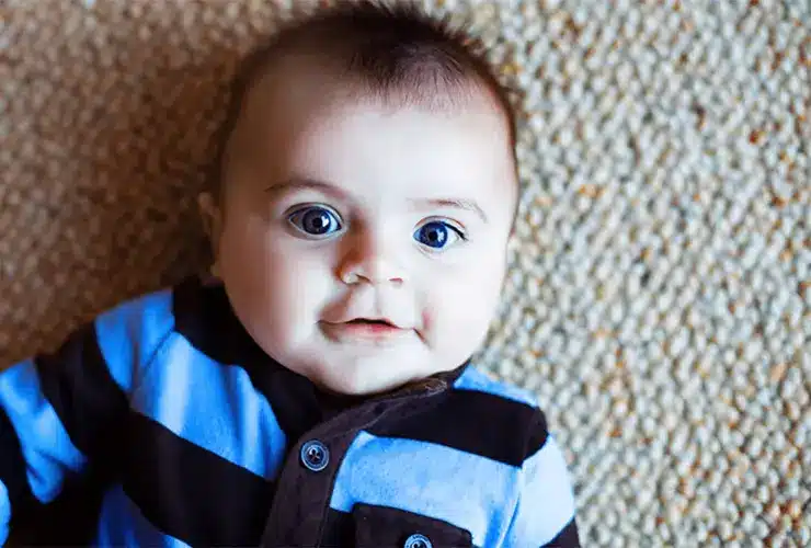 A baby with epilepsy laying down and smiling.