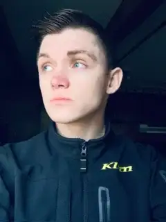 Photo of young man looking off to the side wearing dark clothing.