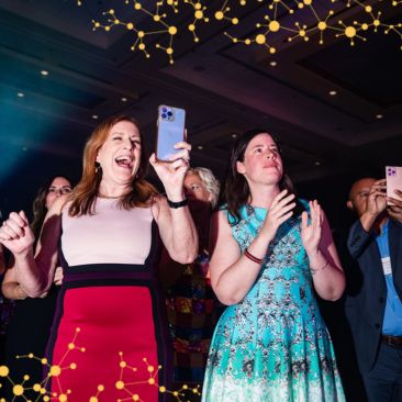 Two women excitedly enjoy a live musical performance at CURE Epilepsy's Night of Discovery.
