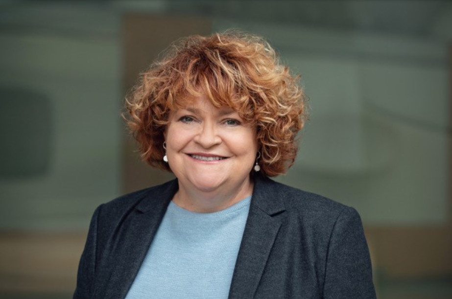 Woman with short hair wearing business attire smiles for a clear headshot.
